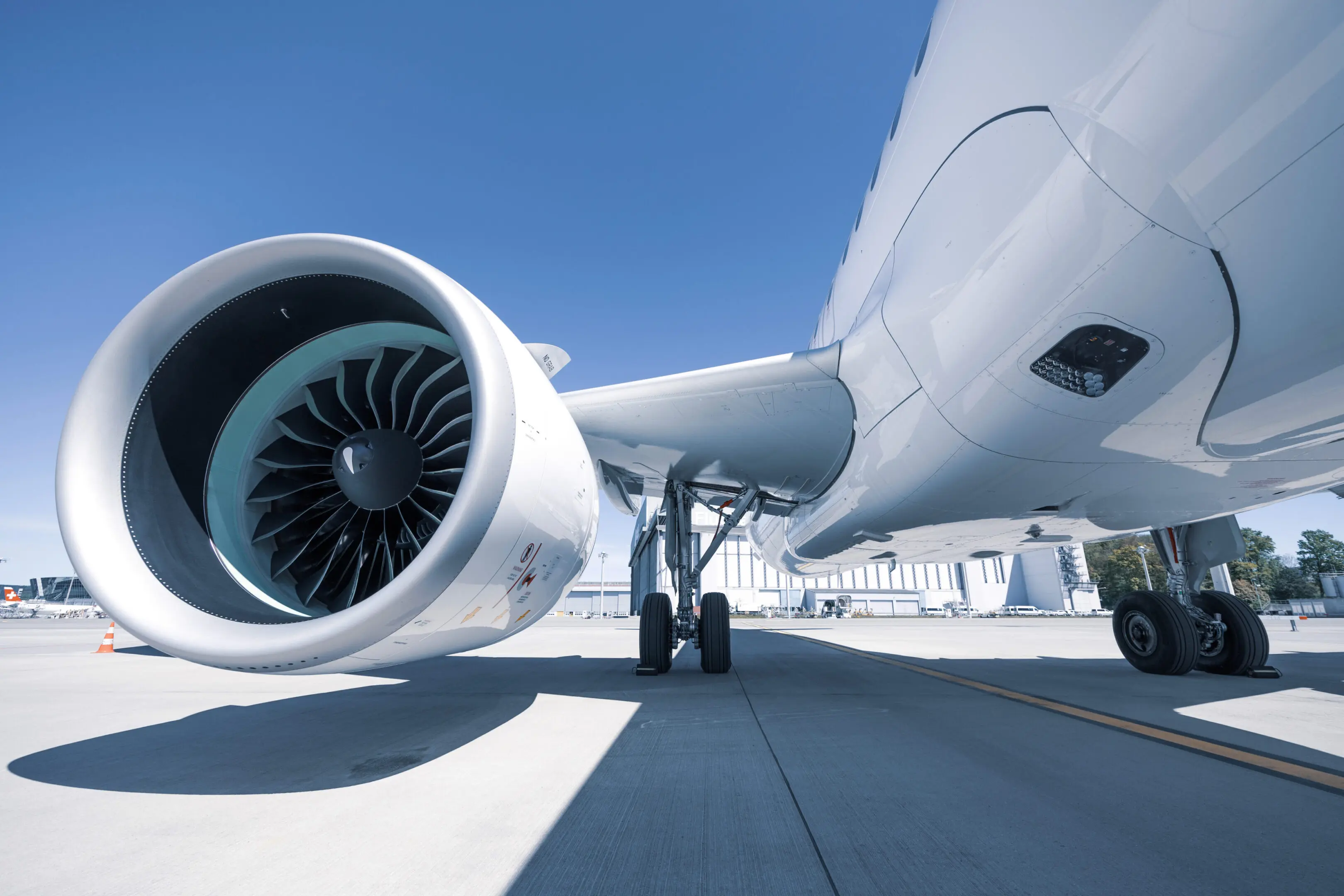Close-up of an airplane engine and landing gear on a sunny day.