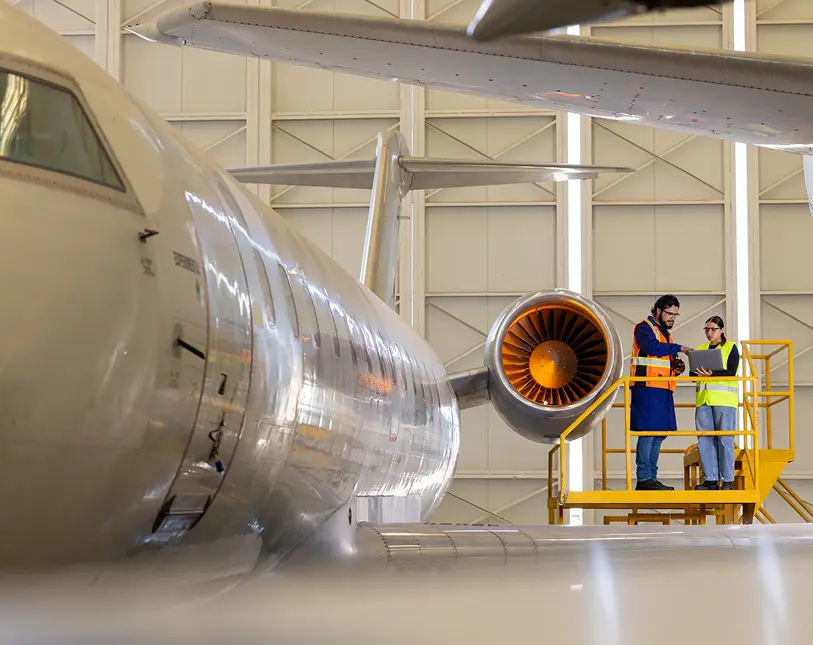 Technicians inspecting jet engine in hangar.