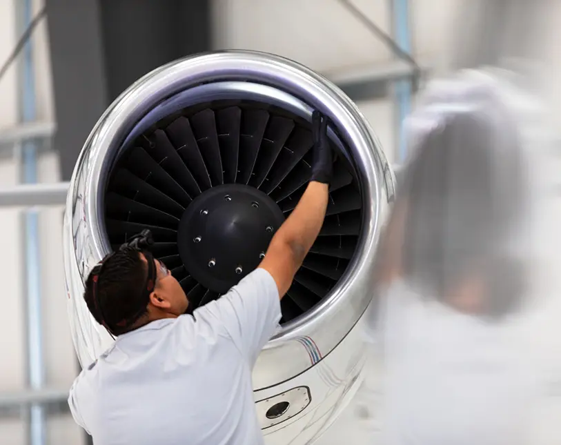 Technician inspecting a jet engine fan blade.