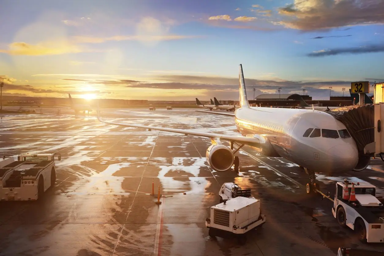 An airplane at a snowy airport during sunset.