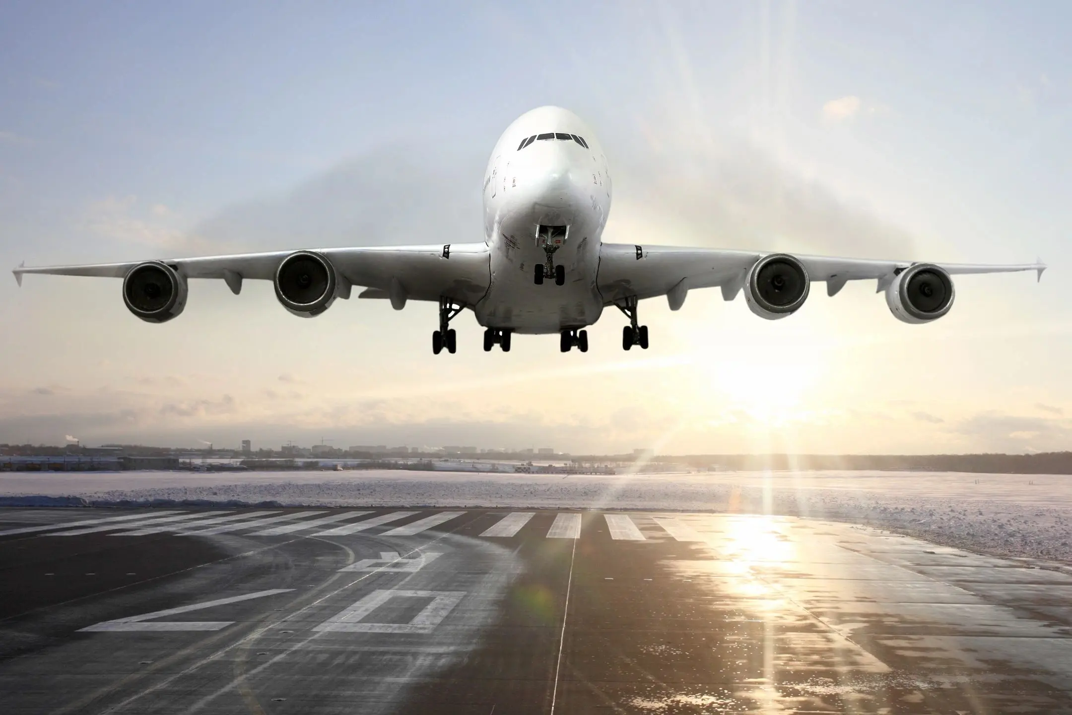 Airplane taking off from a runway at sunset.