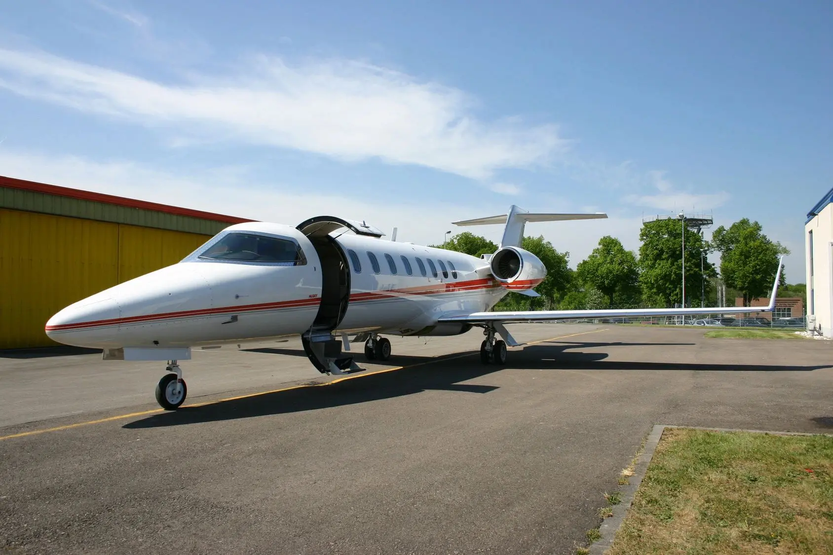 Private jet parked on runway under clear sky.