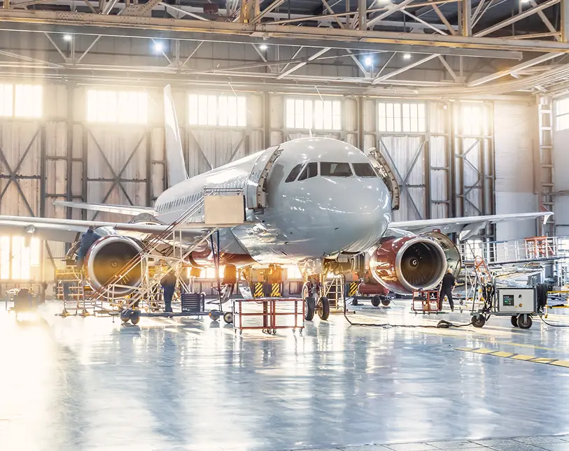 Airplane undergoing maintenance in spacious hangar.